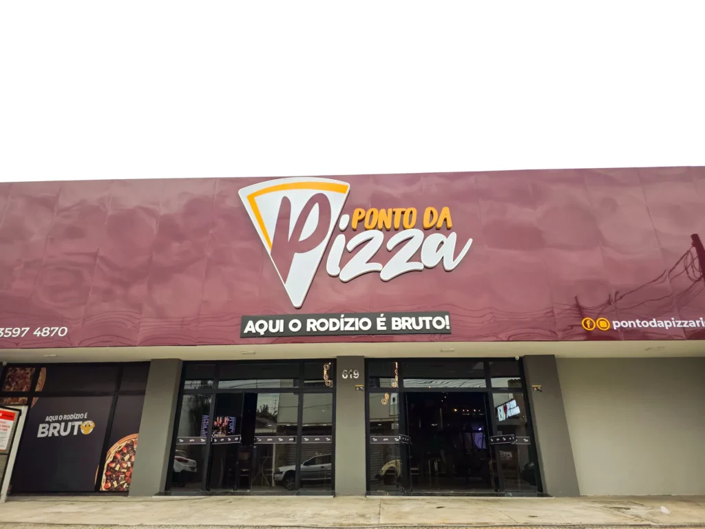 Fachada do Ponto da Pizza Rio Claro durante o dia, com o letreiro sobre as portas de vidro