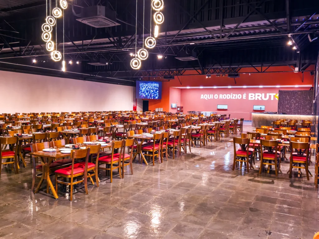 Salão do Ponto da Pizza Rio Claro com mesas postas e a faixa Aqui o rodízio é bruto na parede do fundo