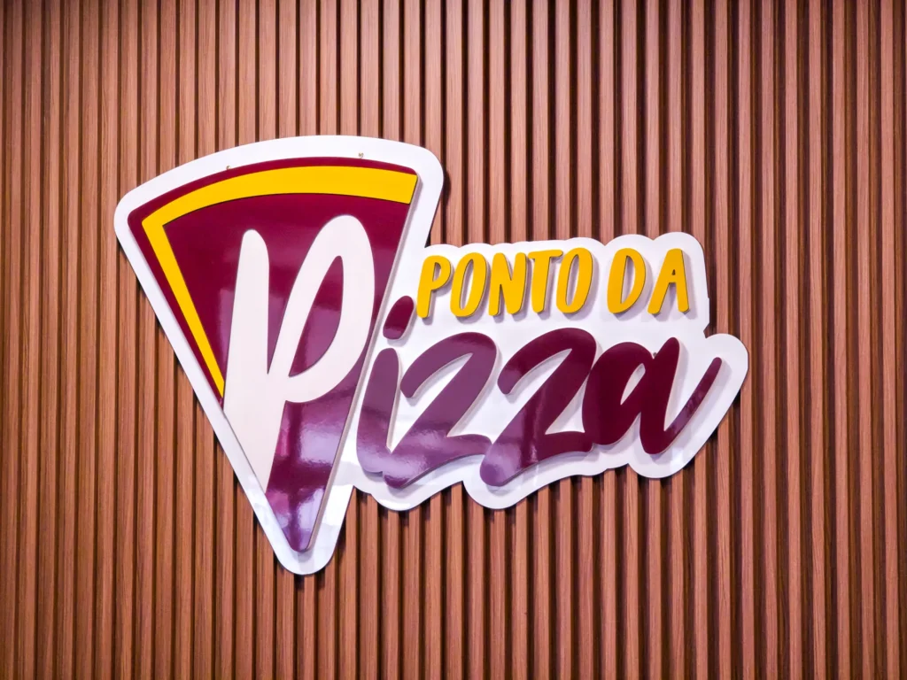 Logotipo do Ponto da Pizza em relevo sobre painel ripado de madeira