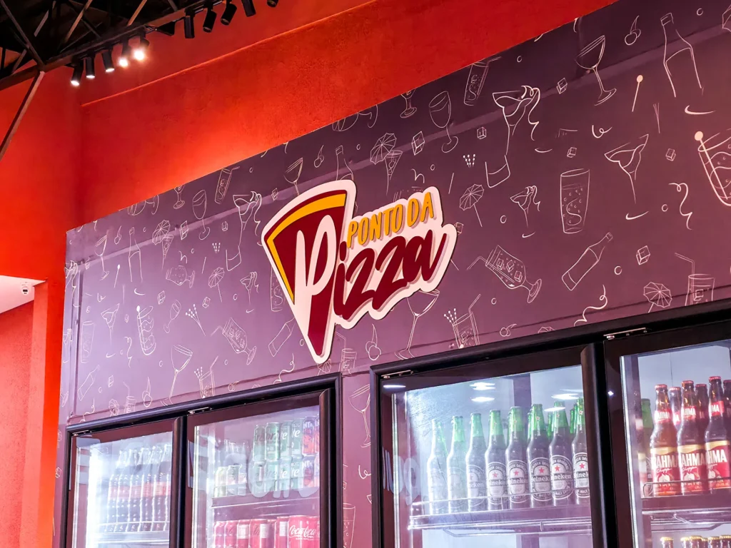 Painel ilustrado com o logotipo do Ponto da Pizza acima das geladeiras de bebidas