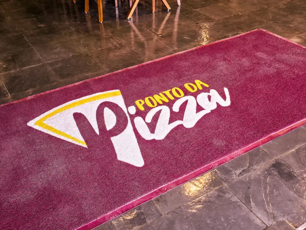 Tapete vinho com o logotipo do Ponto da Pizza sobre piso de pedra